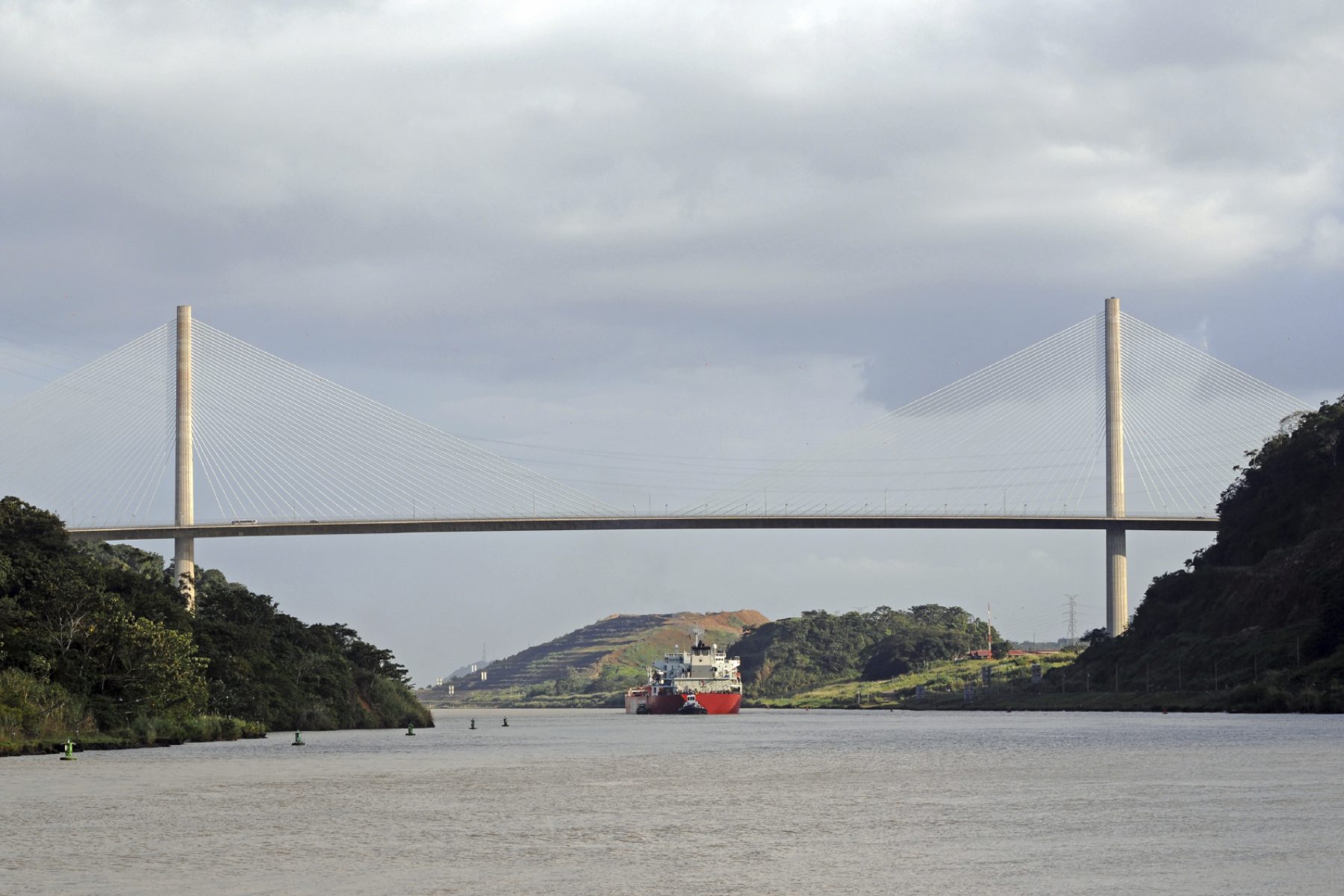 Tanker assisted by two tugboats passing under the Centennail Bridge in the Panama Canal.